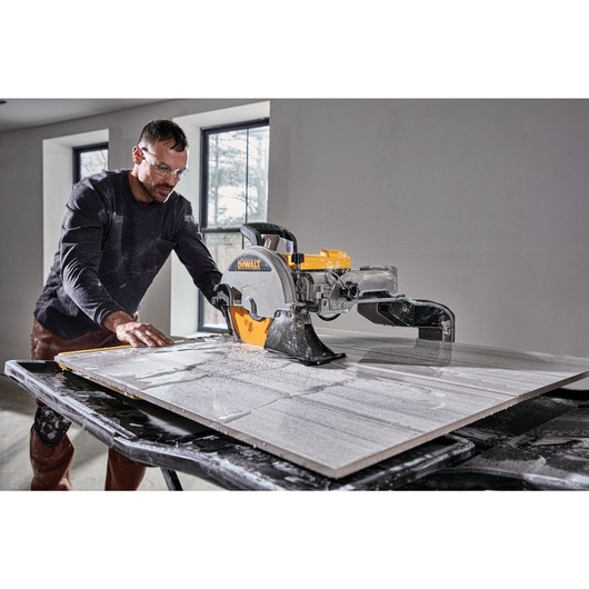 High Capacity Wet Tile Saw being used by a construction worker to cut square tile High Capacity Wet Tile Saw being used by a construction worker to cut square tile