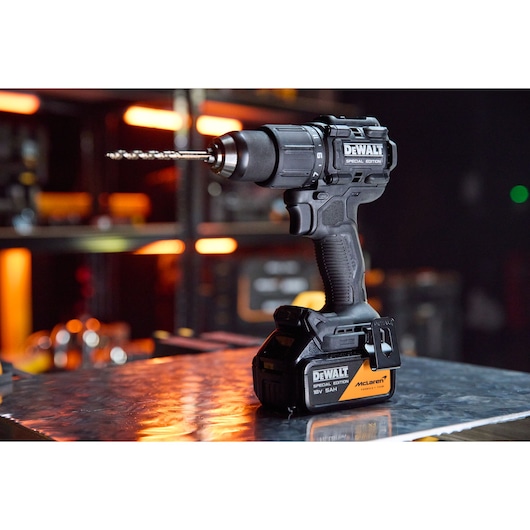 DEWALT x McLaren F1 Team 18V XR Special Edition Hammer Drill Driver with 5Ah battery standing on a metal sheet
