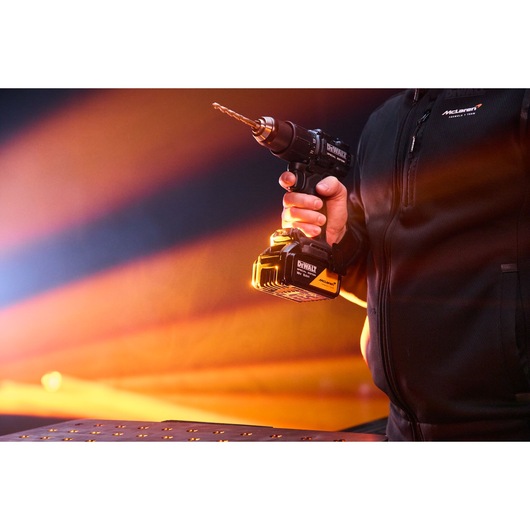 A hand holds the DEWALT x McLaren F1 Team 18V XR Special Edition Hammer Drill Driver with 5Ah battery