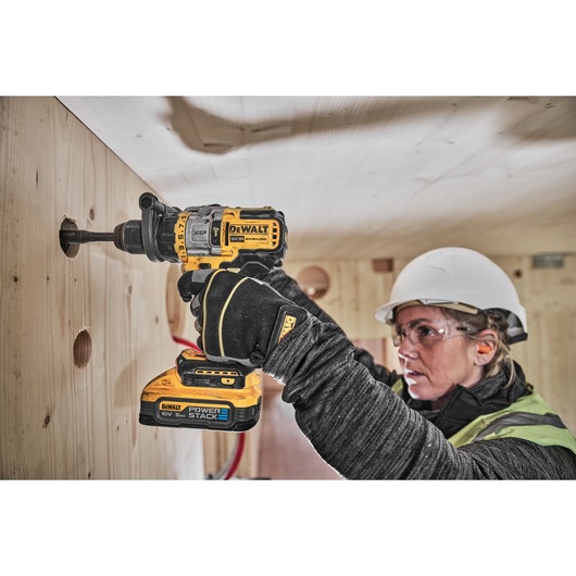 18V XR Brushless drill driver with Powerstack battery cutting hole into wooden wall