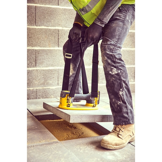 Construction worker uses the straps of a Grabo 18V XR Suction Lifter to lower a concrete block into position