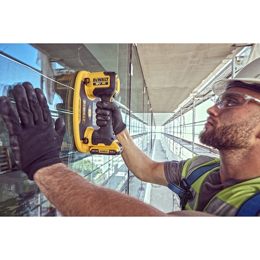 Construction worker holds a Grabo 18V XR Suction Lifter attached to a pane of glass