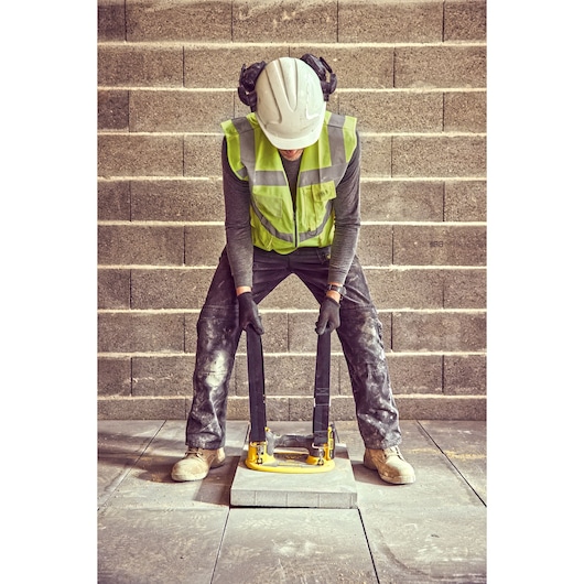 Construction worker uses the straps of a Grabo 18V XR Suction Lifter to lower a concrete block into position