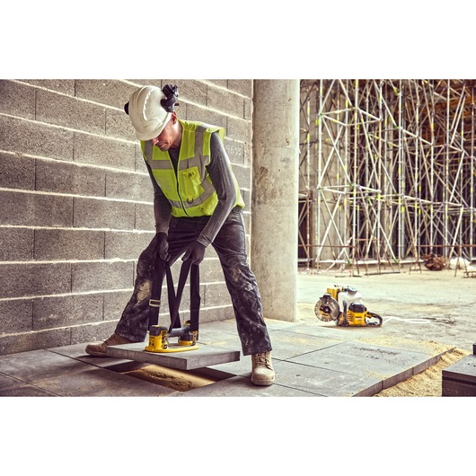 Construction worker uses the straps of a Grabo 18V XR Suction Lifter to lower a concrete block into position