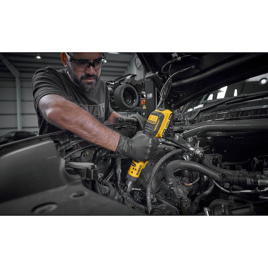 Mechanic using the DEWALT 18V XR Brushless _� Extended Ratchet with 18V POWERSTACK battery to tighten bolts on engine