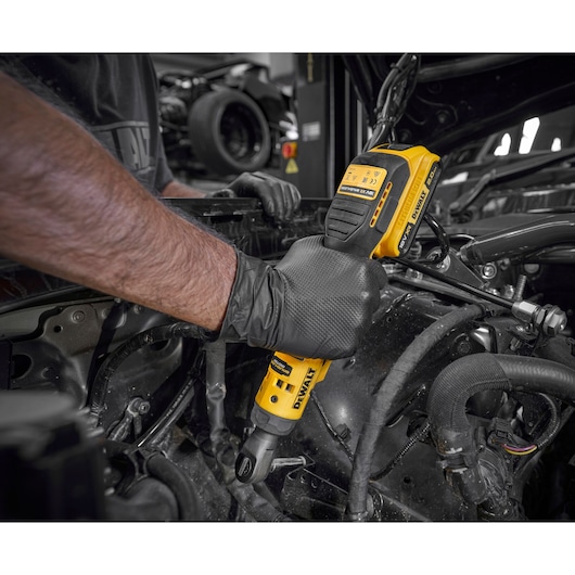 Mechanic using the DEWALT 18V XR Brushless ½” Extended Ratchet with 18V POWERSTACK battery to tighten bolts on engine