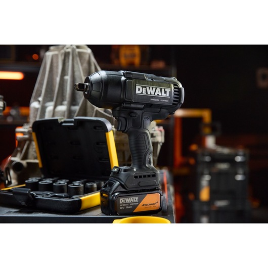 DEWALT x McLaren F1 Team 18V XR Special Edition Impact Wrench with 5Ah battery standing on a storage box alongside a socket set