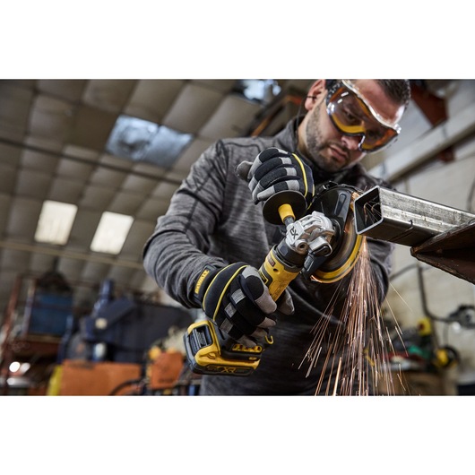 Worker uses the DEWALT 18V XR Compact 125mm Angle Grinder to cut steel square tubing