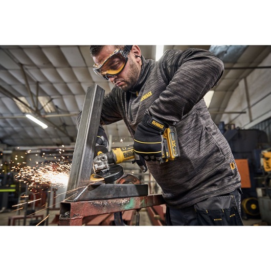 Worker uses the DEWALT 18V XR Compact 125mm Angle Grinder with 3.5ah battery to grind steel square tubing