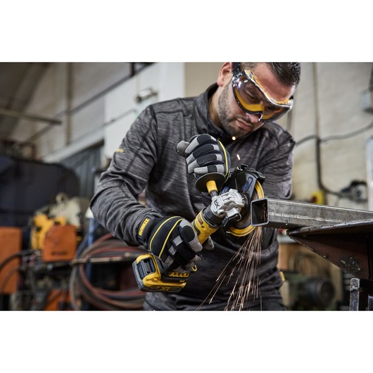 Worker uses the DEWALT 18V XR Compact 125mm Angle Grinder with 3.5ah battery to cut steel square tubing