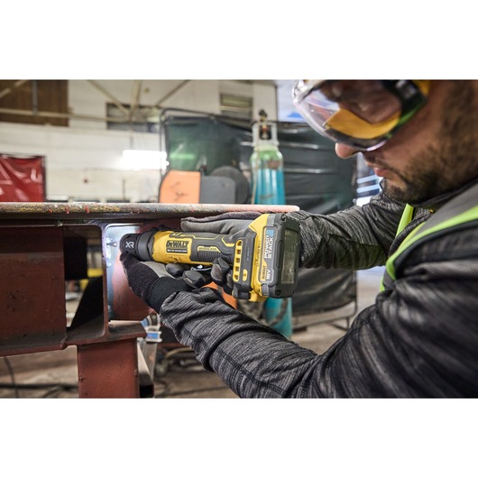 Worker uses the DEWALT 18V XR Compact Inline Grinder to smooth a metal surface