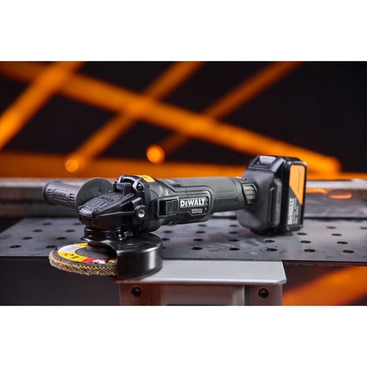 DEWALT x McLaren F1 Team 18V XR Special Edition Grinder with 5Ah battery sitting on a metal sheet