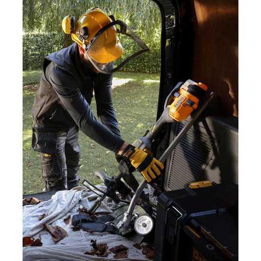 A folded DEWALT 54V XR FLEXVOLT Split Boom with Edger Attachment being placed into a van 