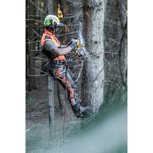 Arborist at height chopping tree with the DCMCST635 Top Handle Chainsaw