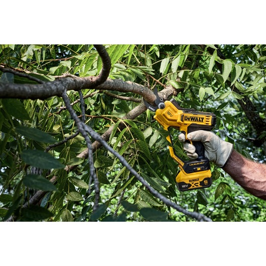 User trimming leaves using powered cordless pruner User trimming leaves using powered cordless pruner