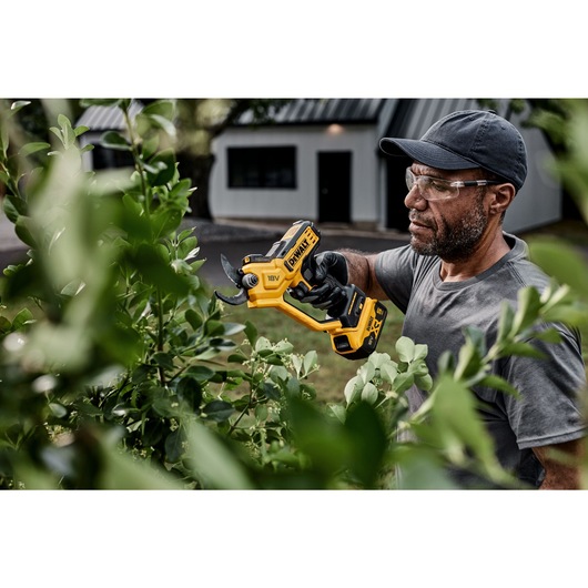 User trimming leaves using powered cordless pruner User trimming leaves using powered cordless pruner