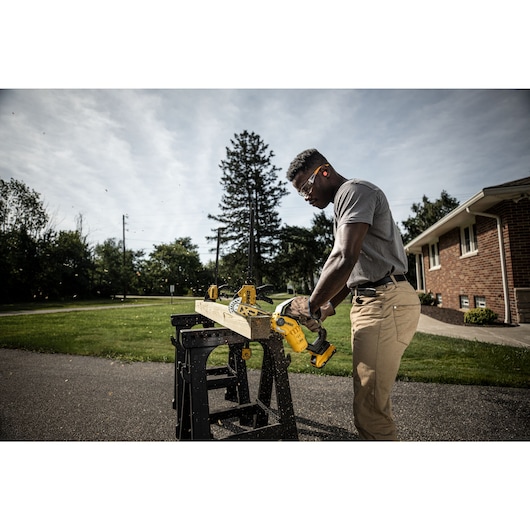 Clamped lumber on a saw horse being cut with an 18V XR Brushless Chain Saw  