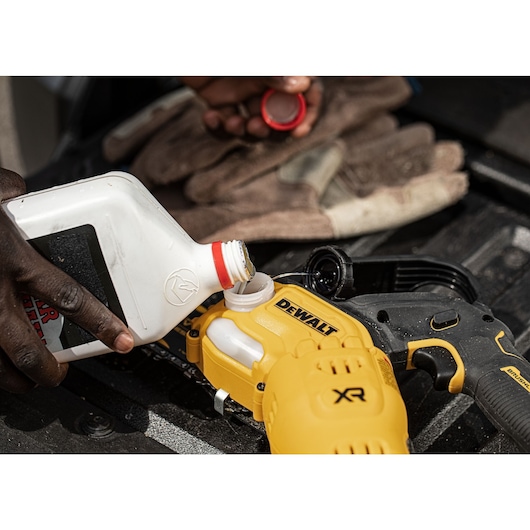 Oil being poured into an 18V XR Brushless Chain Saw