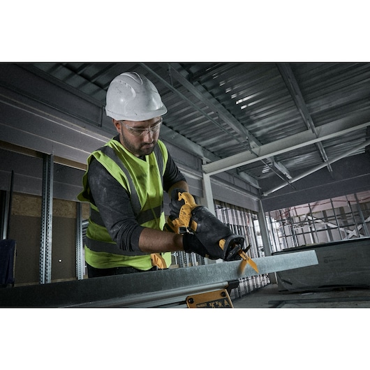 Workman using a reciprocating saw to cut metal Workman using a reciprocating saw to cut metal