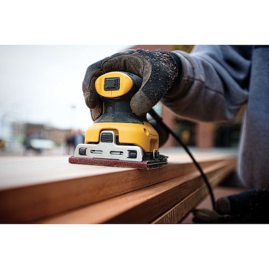 One quarter inch sheet palm grip sander sanding a wooden sheet. One quarter inch sheet palm grip sander sanding a wooden sheet.