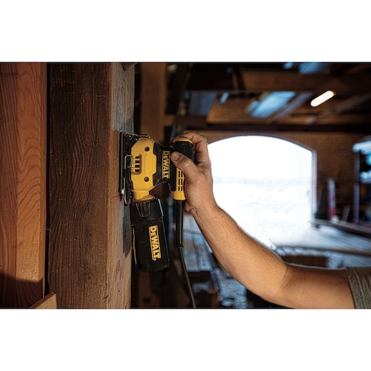 One quarter inch sheet palm grip sander sanding on a wooden wall at a worksite. One quarter inch sheet palm grip sander sanding on a wooden wall at a worksite.