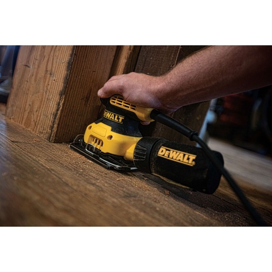 One quarter inch sheet palm grip sander sanding at corner of a wooden structure. One quarter inch sheet palm grip sander sanding at corner of a wooden structure.