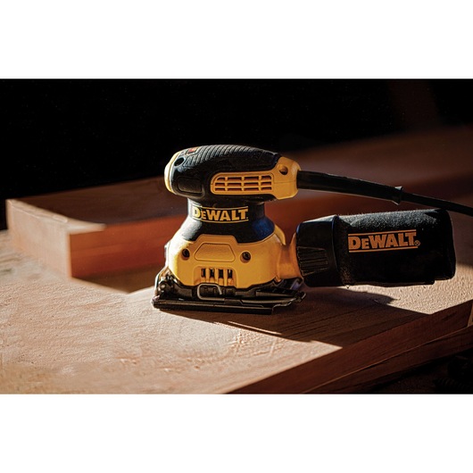 One quarter inch sheet palm grip sander placed on top of a wooden sheet. One quarter inch sheet palm grip sander placed on top of a wooden sheet.