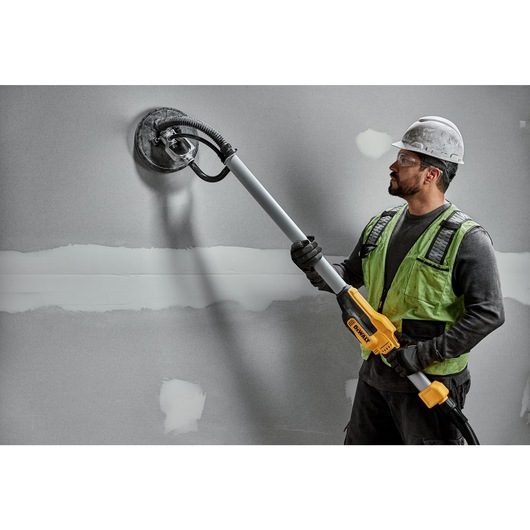 Electric drywall sander polishing wall.
