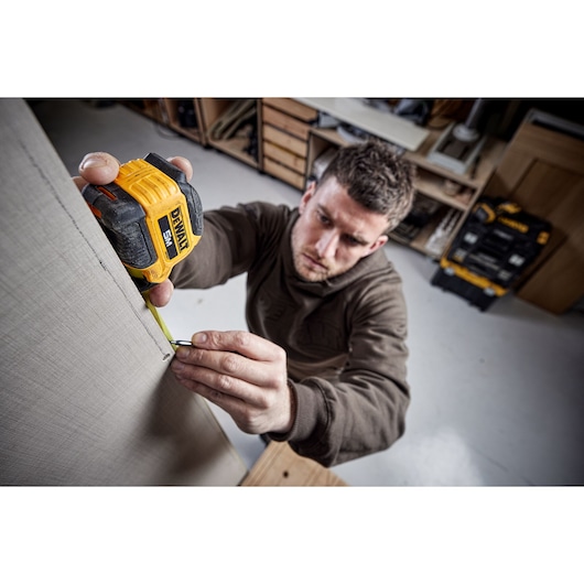 Man measuring with 5 meter compact tape Man measuring with 5 meter compact tape