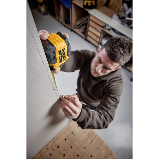 Man measuring with 5 meter compact tape Man measuring with 5 meter compact tape