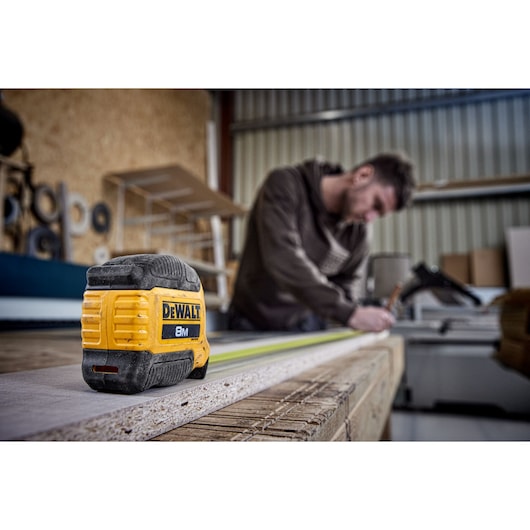 Man measuring with 8 meter compact tape, product focus Man measuring with 8 meter compact tape, product focus