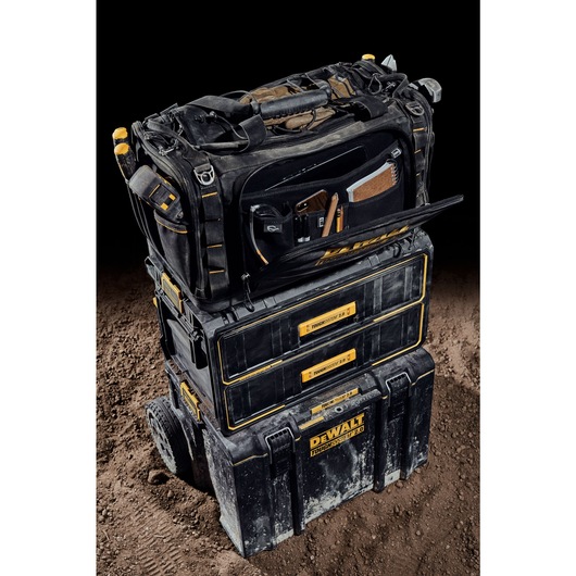 Front view of the DEWALT TOUGHSYSTEM 2.0 22-inch jobsite soft storage toolbag with front pocket open holding various tools on top of TOUGHSYSTEM 2.0 two-drawer organizer. Front view of the DEWALT TOUGHSYSTEM 2.0 22-inch jobsite soft storage toolbag with front pocket open holding various tools on top of TOUGHSYSTEM 2.0 two-drawer organizer.