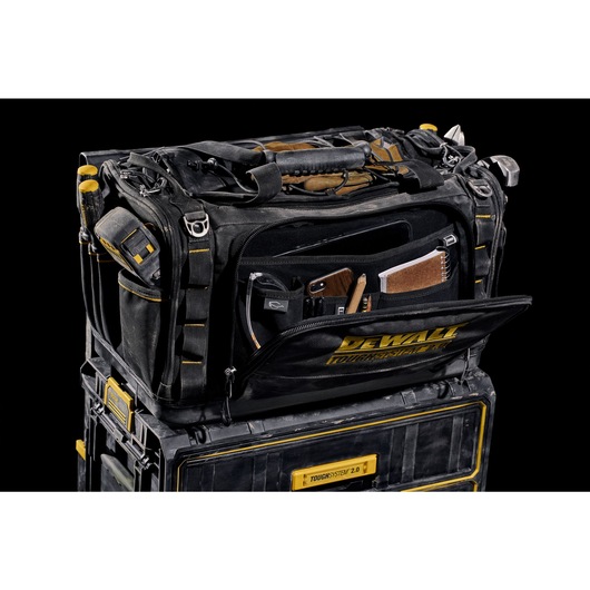 Front view of open DEWALT TOUGHSYSTEM 2.0 22-inch jobsite soft storage toolbag holding DEWALT screwdrivers and other hand tools and open front pocket hold notebook, phone and pencils.