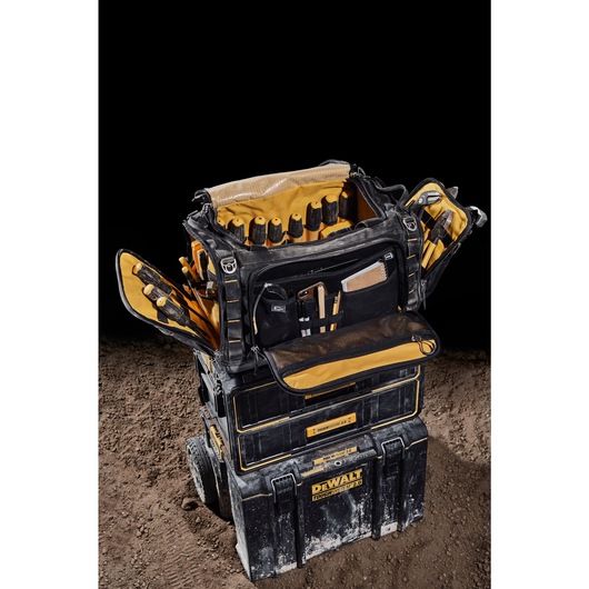 Three quarter view of the DEWALT TOUGHSYSTEM 2.0 22-inch jobsite soft storage toolbag with open front pocket holding notebook, phone and pencils sitting on TOUGHSYSTEM 2.0 two-drawer organizer. Three quarter view of the DEWALT TOUGHSYSTEM 2.0 22-inch jobsite soft storage toolbag with open front pocket holding notebook, phone and pencils sitting on TOUGHSYSTEM 2.0 two-drawer organizer.
